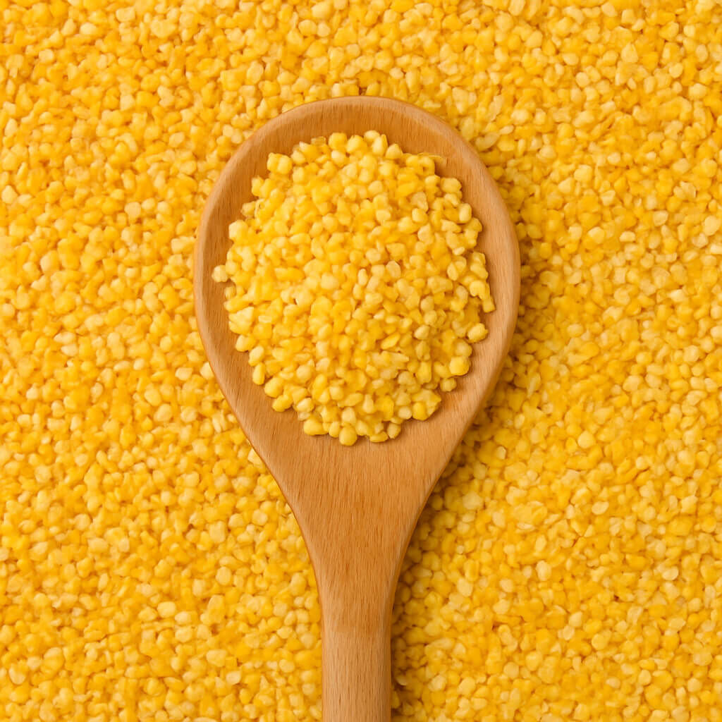 Close-up of yellow corn grits in wooden spoon