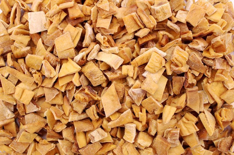 Nærbillede af tørrede, hakkede æblestykker i lysebrune nuancer, spiseklare og perfekte til bagning, müsli eller som snacks