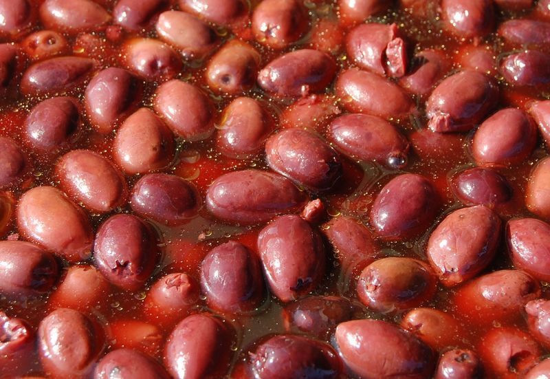 Nahaufnahme von dunkelvioletten Kalamata-Oliven in Olivenöl mit glänzender Oberfläche