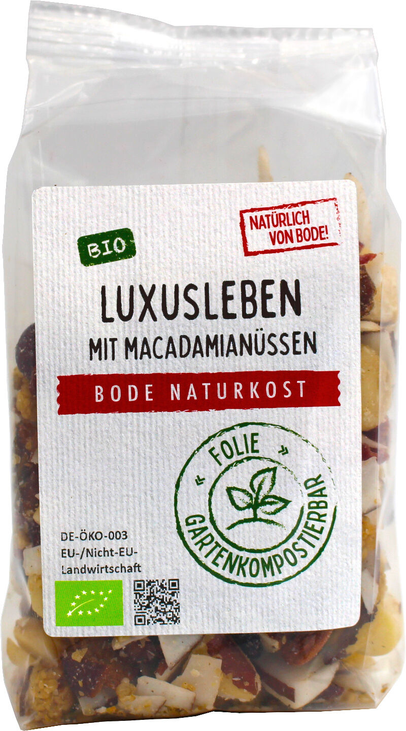 Gennemsigtig plastikpose med hvid etiket: 'Luxusleben mit Macadamianüssen' fra Bode Naturkost. Økologisk snackblanding med macadamianødder og tørrede frugter; etiketten viser 'BIO' og et stempel om havekomposterbar folie.