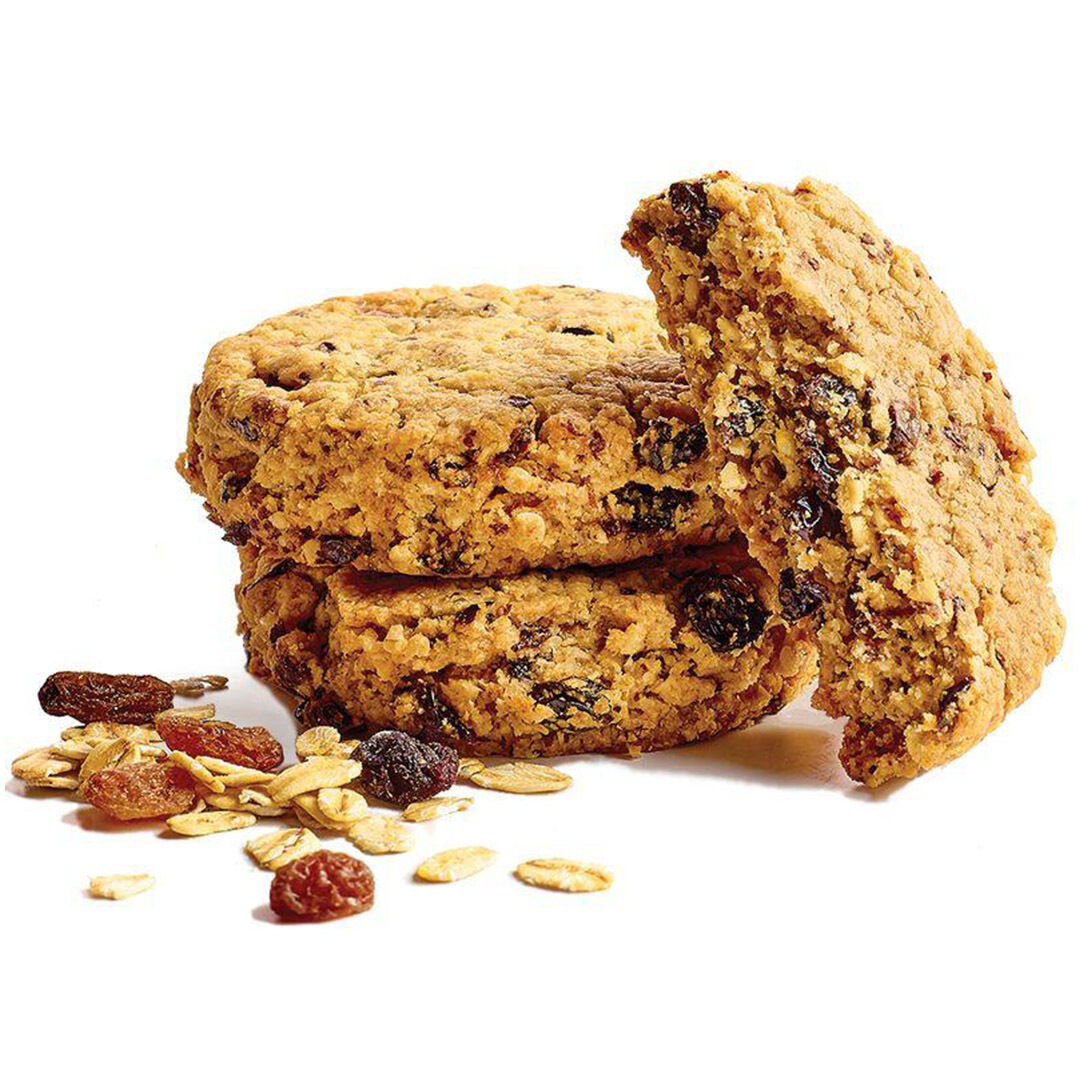 Stak af tre havregrynscookies med rosiner, hvor den øverste er delt, på hvid baggrund med løse havreflager og rosiner