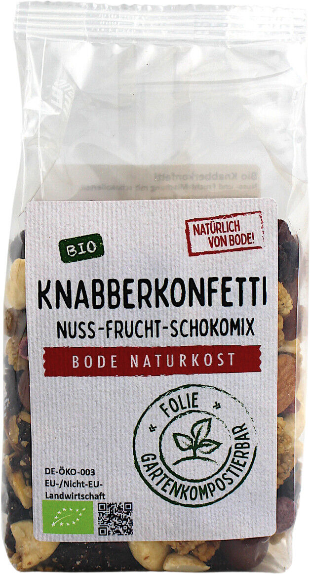 Gennemsigtig plastikpose med Knabberkonfetti nødde-frugt-chokomix (økologisk) fra Bode Naturkost; man kan se nødder og tørret frugt gennem posen og en hvid etiket med mærket 'havekomposterbar folie'.