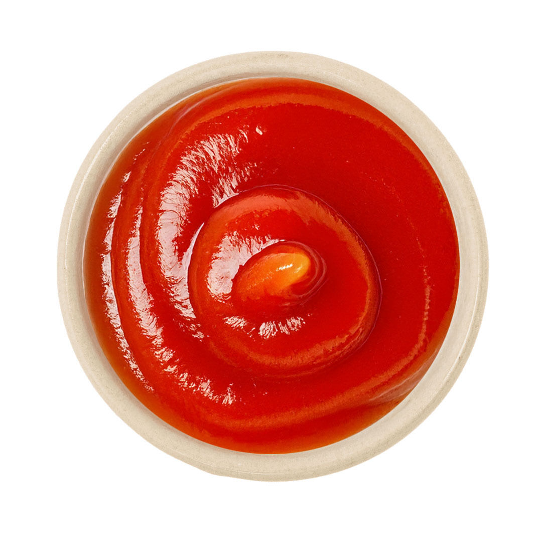 Schälchen mit glänzendem, tiefrotem Ketchup in spiralförmiger Form auf weißem Hintergrund