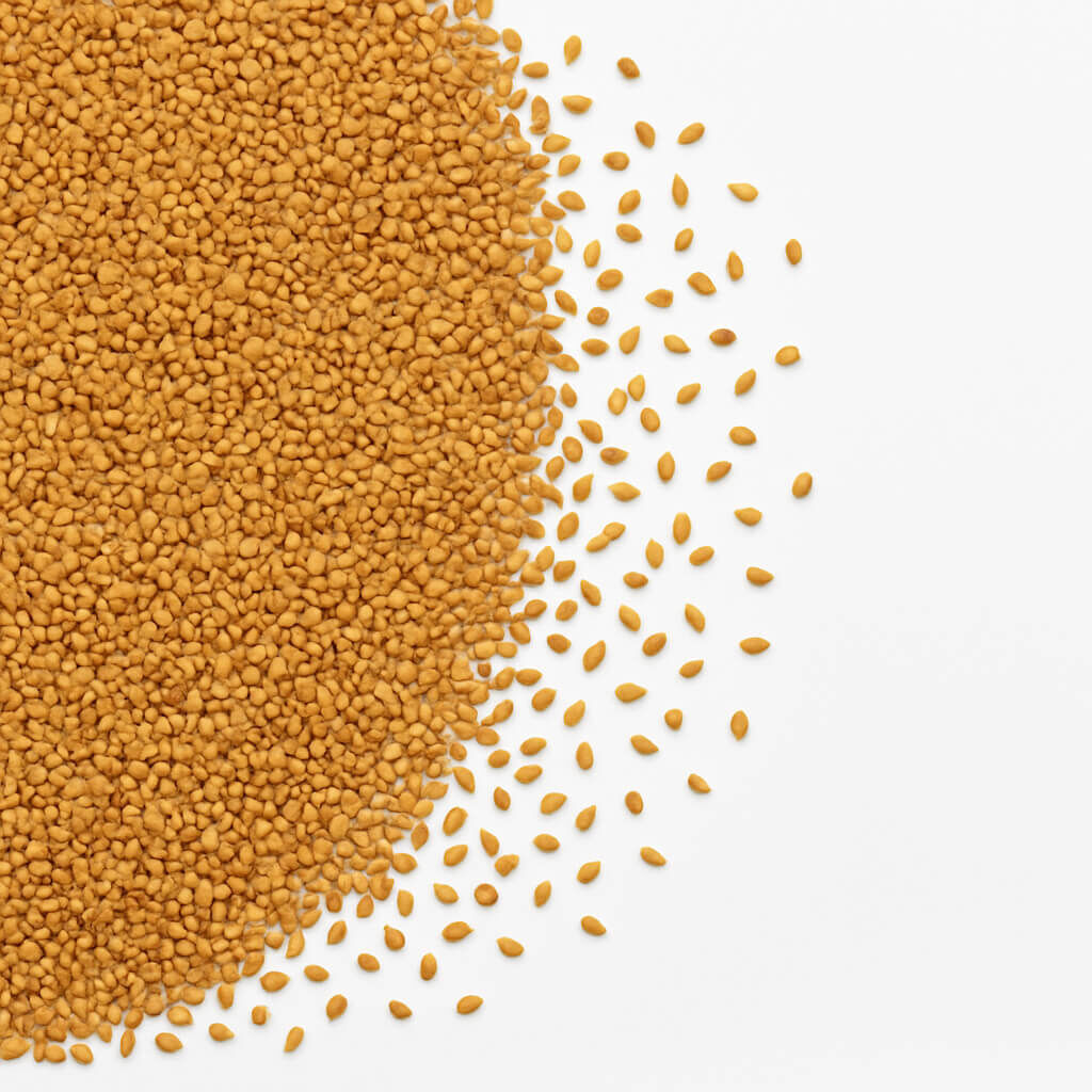 Close-up of small golden seeds on white surface