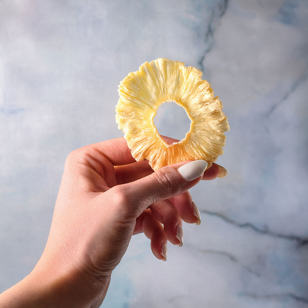Hand holding a dried pineapple ring