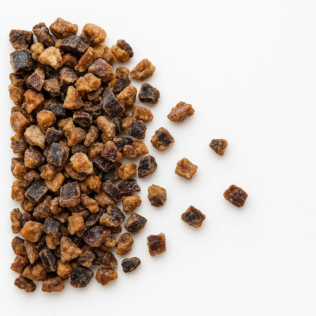 Brown dried fruit cubes on white background
