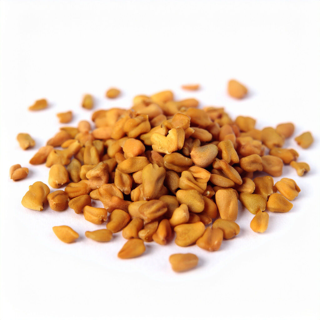 Nærbillede af en bunke gyldne bukkehornsfrø (fenugreek) spredt på hvid baggrund, der fremhæver frøenes form og tekstur.