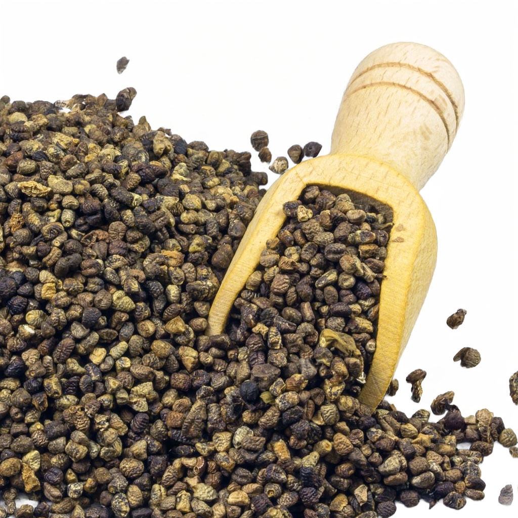 Nærbillede af tørrede sorte peberkorn spredt på hvid baggrund med en træske