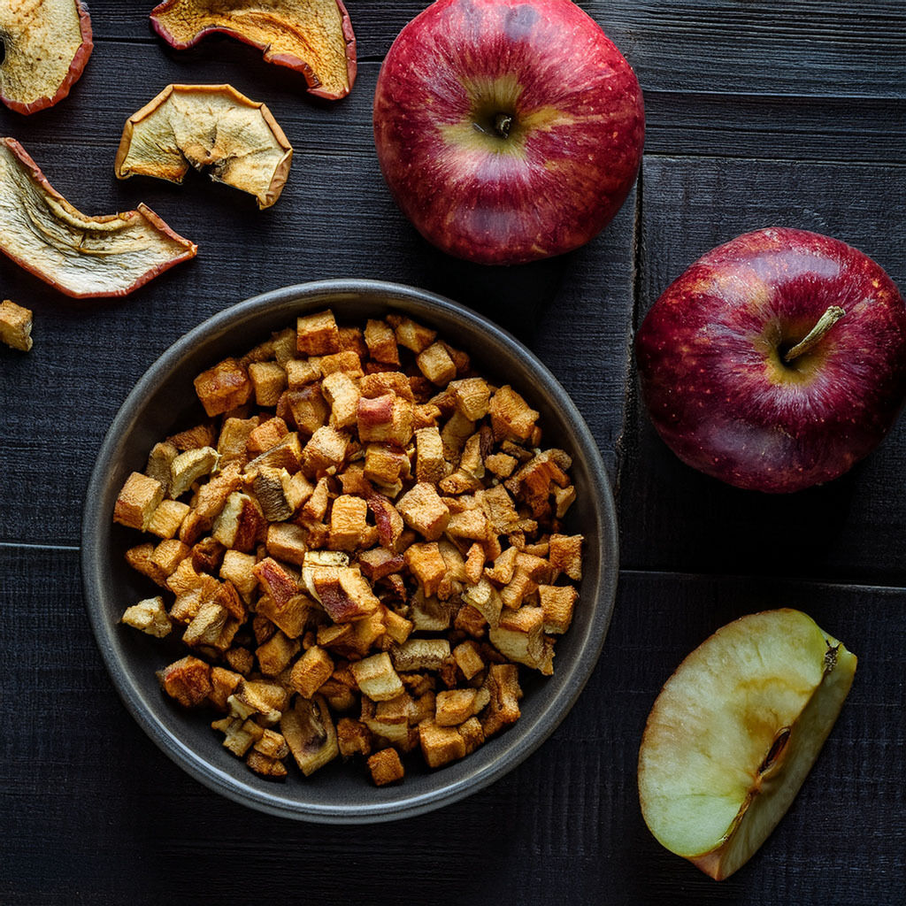 Bowl of dried apple cubes with fresh red apples