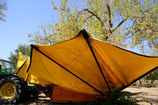 Folded yellow sun canopy attached to a tractor in an orchard