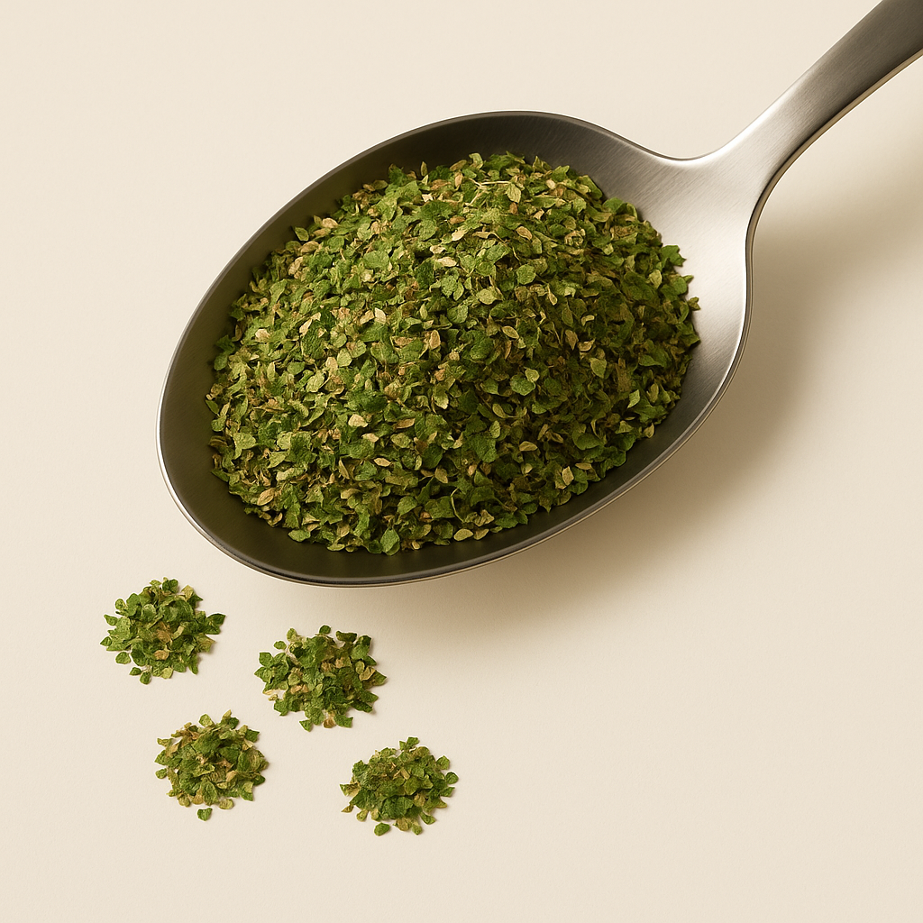 Spoon filled with dried oregano leaves, with some scattered beside it