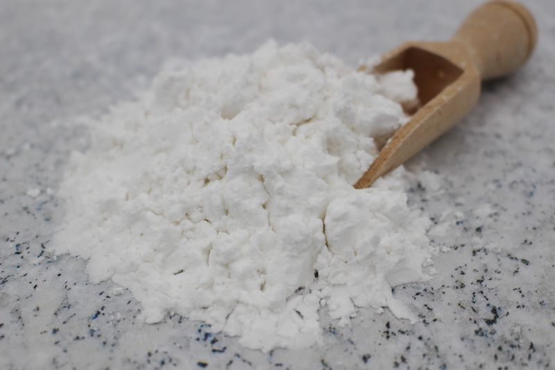 Nærbillede af hvidt pulver i en lille træske på et marmoreret køkkenbord
