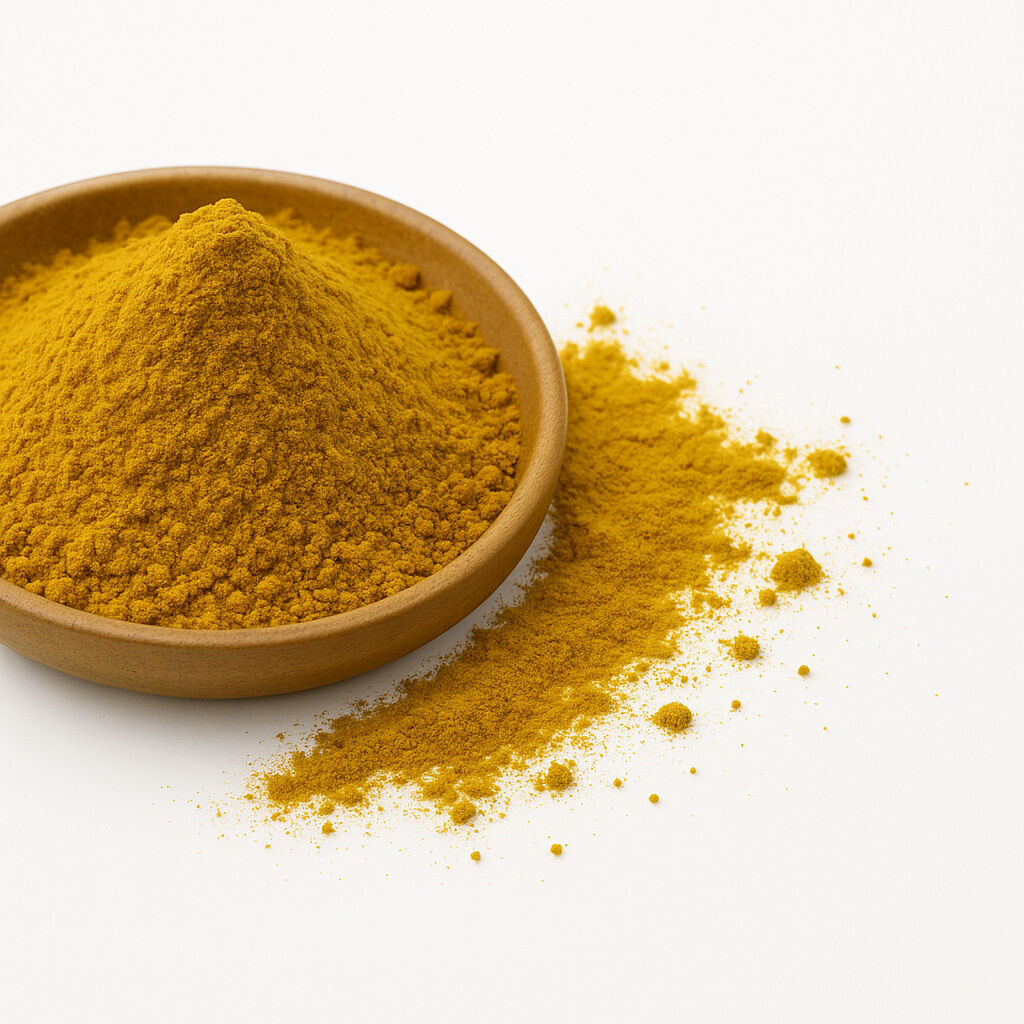 Træskål med et lille bjerg af fintmalet gurkemejepulver og spredt pulver på hvid baggrund