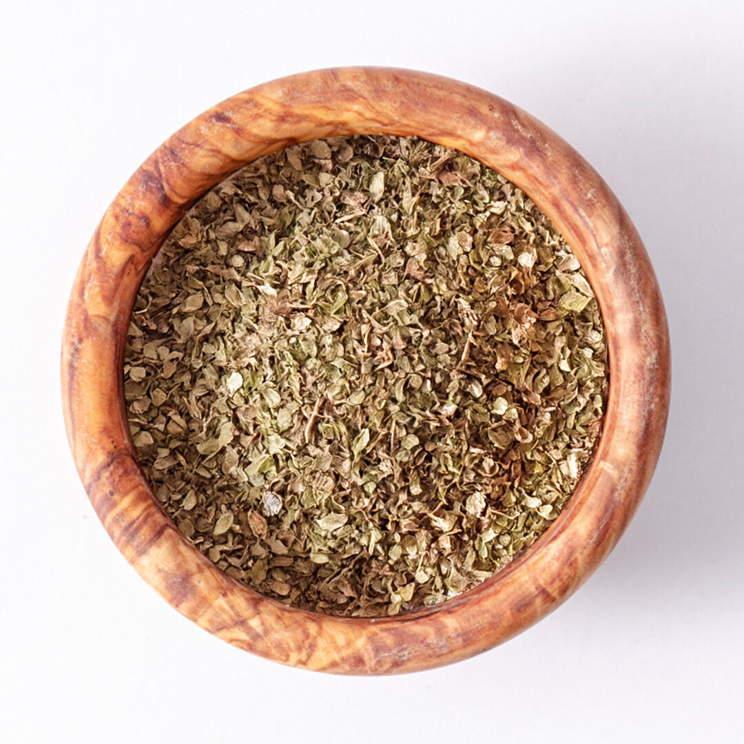 Top view of a wooden bowl filled with dried oregano leaves