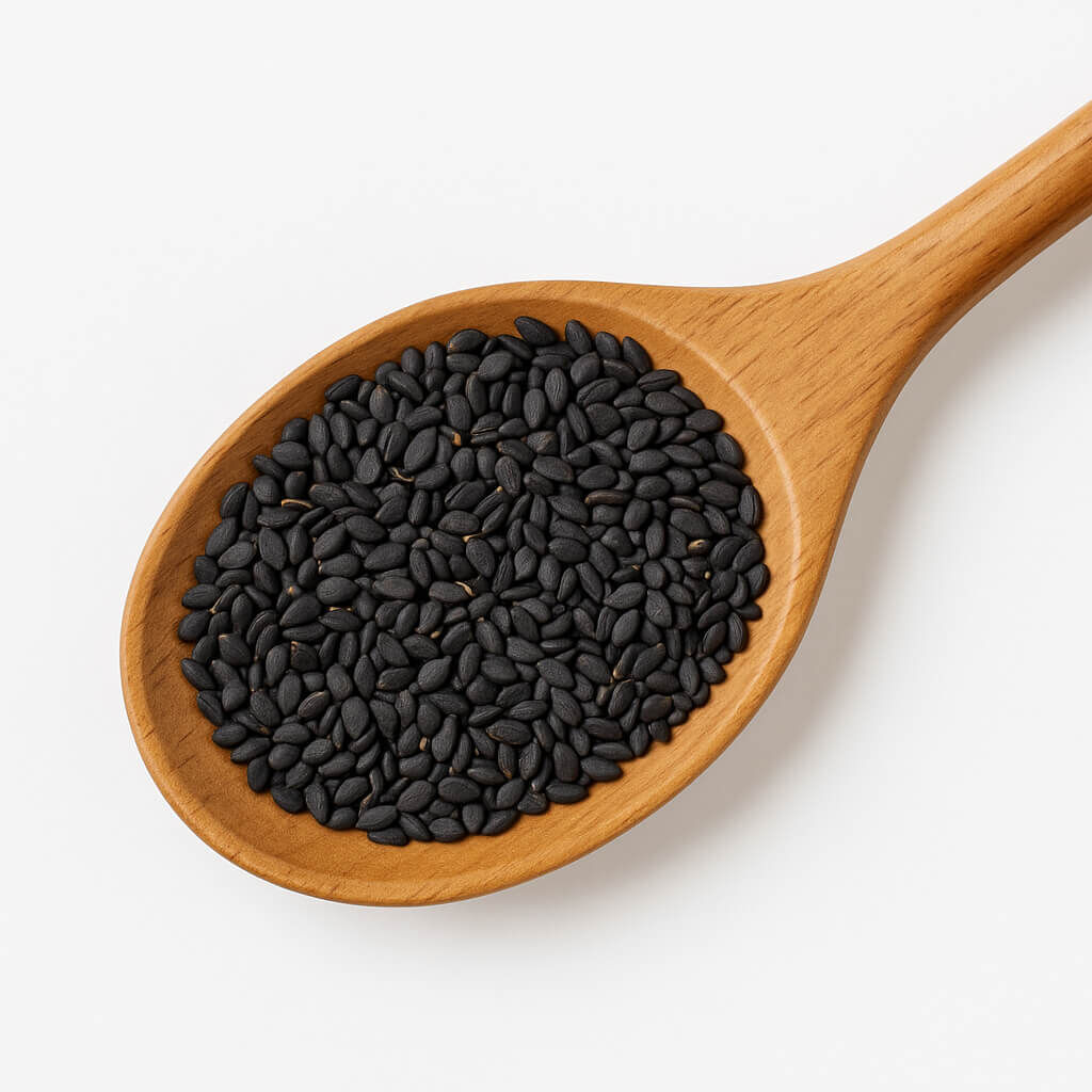 Black sesame seeds in wooden spoon on white background
