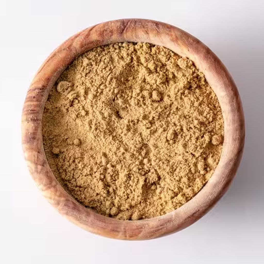 A top view of natural ground spice in a round wooden bowl, placed on a white background.