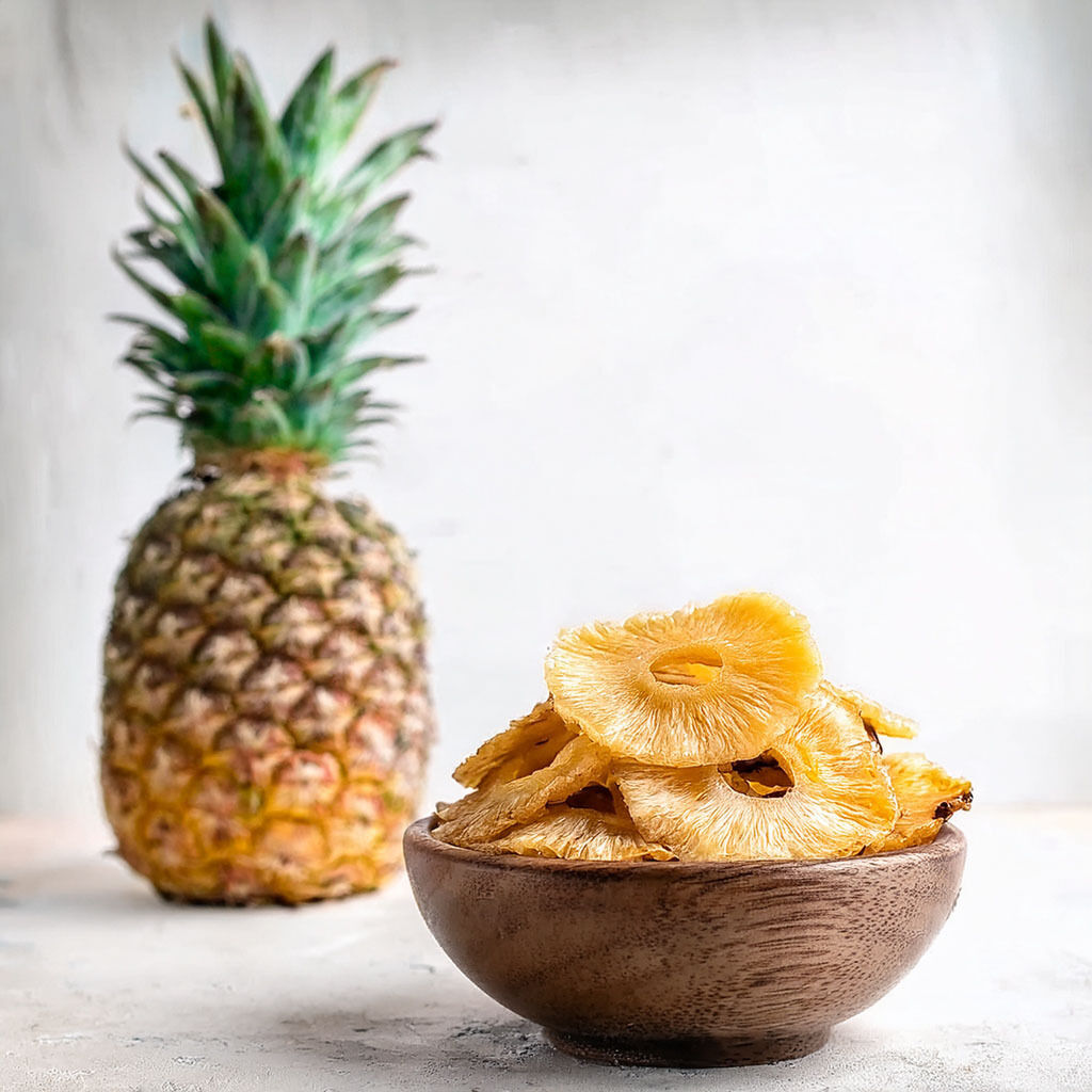 Bowl of dried pineapple rings with whole pineapple