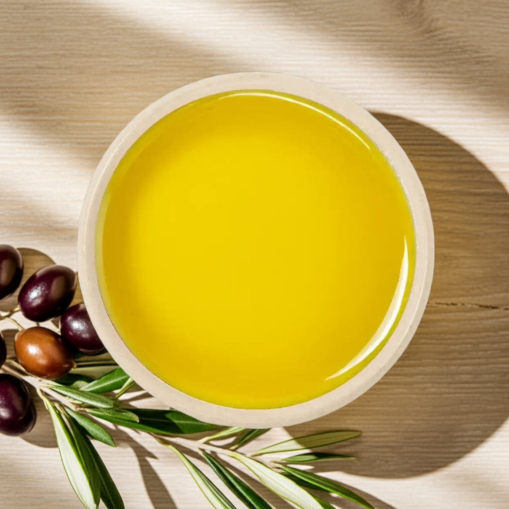 Topvisning af skål med gylden olivenolie, oliven og olivengren på lyst træbord