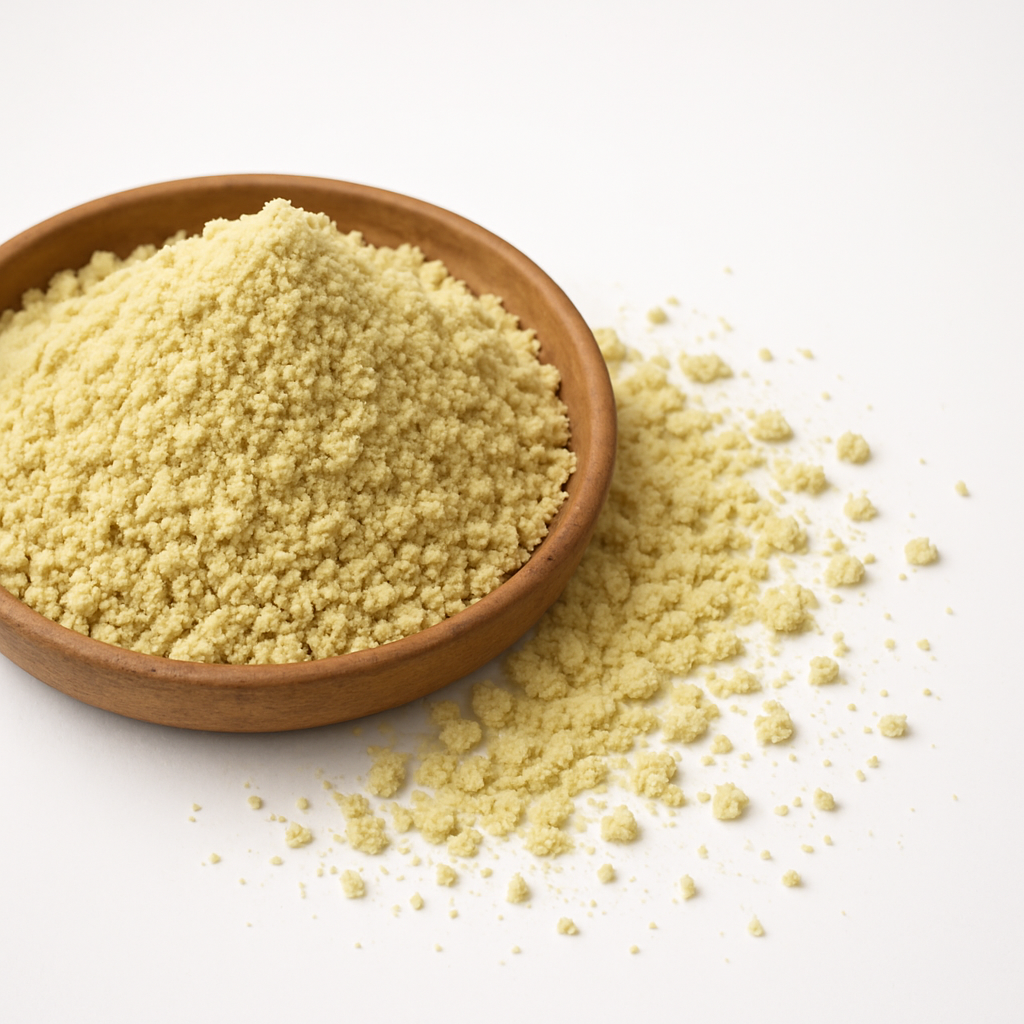 Top view of natural chickpea flour in a wooden bowl with scattered flour on a white background