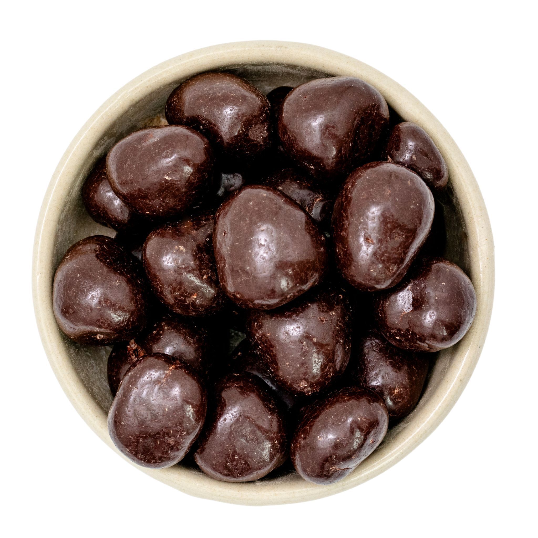 Nahaufnahme einer kleinen Schale mit schokoladenüberzogenen Rosinen, glänzende dunkle Schokoladenhülle
