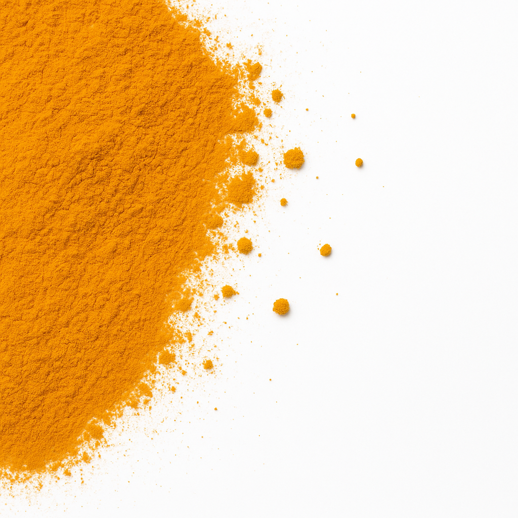 Nærbillede af finmalet gyldent gurkemejepulver spredt på hvid baggrund