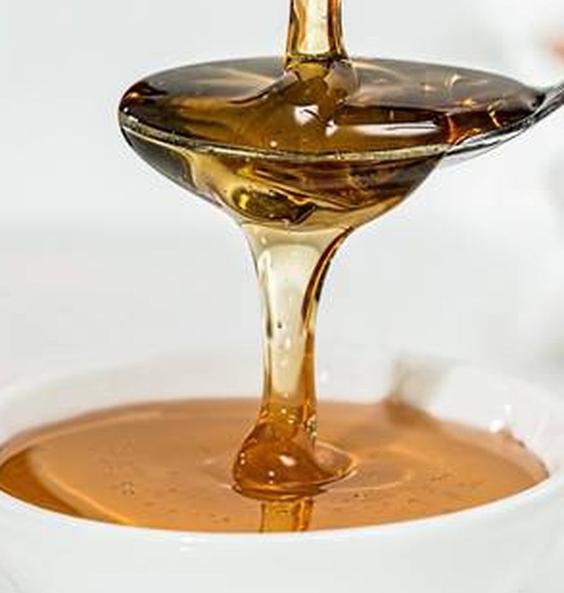Close-up of honey pouring from spoon into bowl