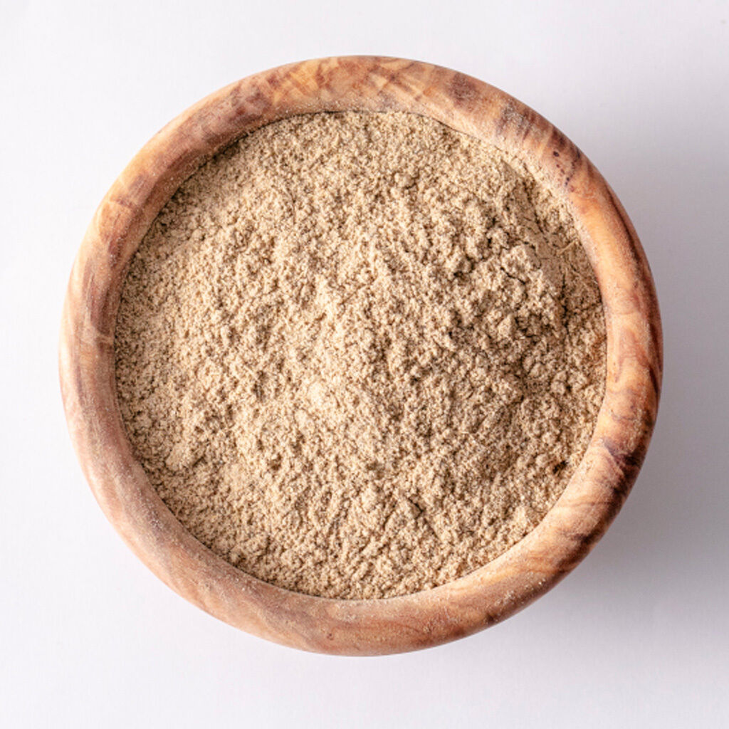 Billede set ovenfra af en rund træskål fyldt med fint lysebrunt pulver med tør, fin tekstur
