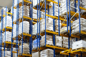 Høje lagerreoler fyldt med indpakkede paller og kasser på et moderne distributionscenter