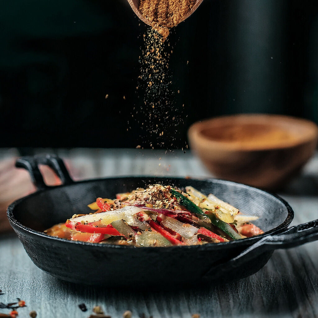 Cooking vibrant vegetable stir-fry with spices in a cast iron pan