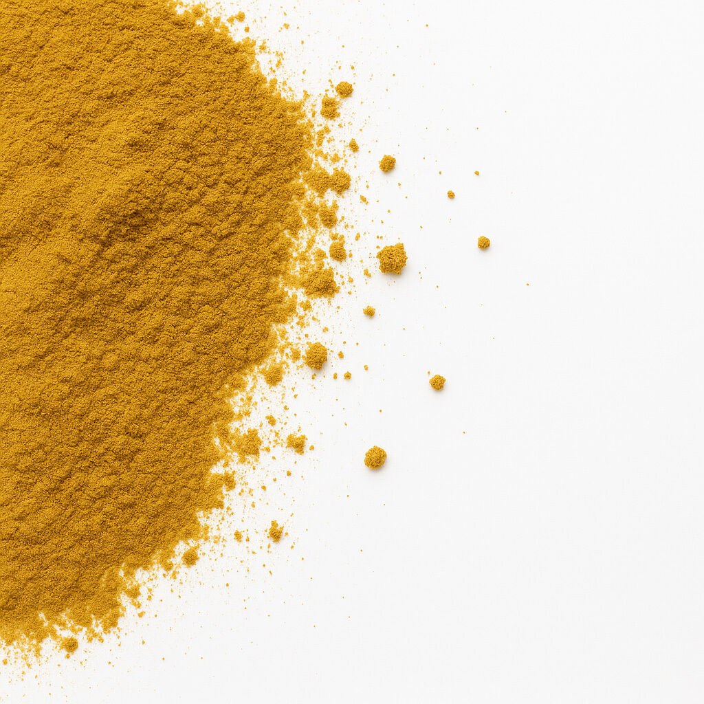 Nærbillede af gul gurkemejepulver spredt i en bunke med løse korn på hvid baggrund