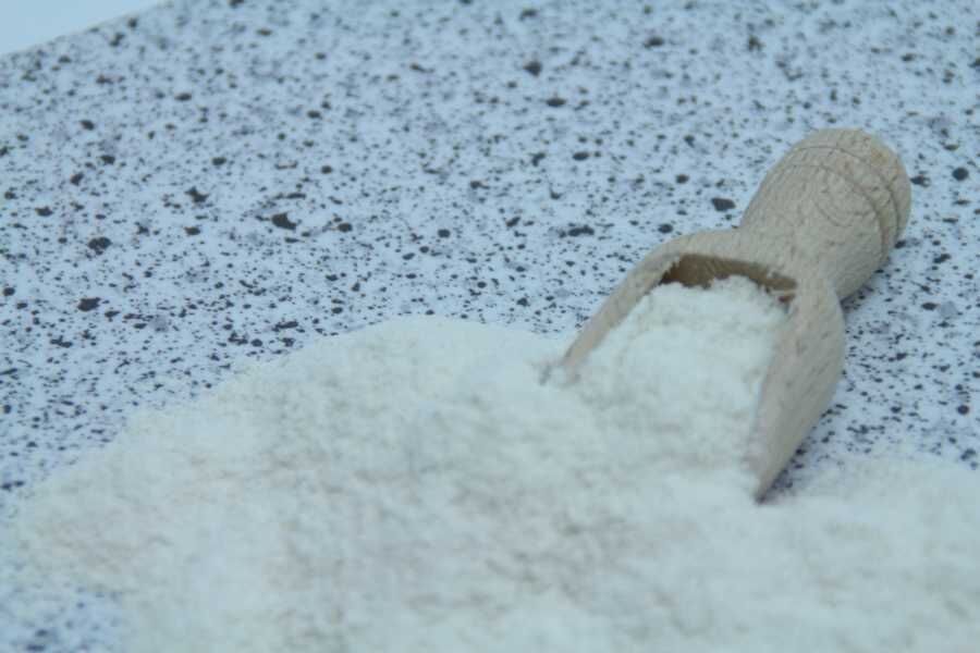 Træske med hvidt mel spredt på en lys, prikket overflade