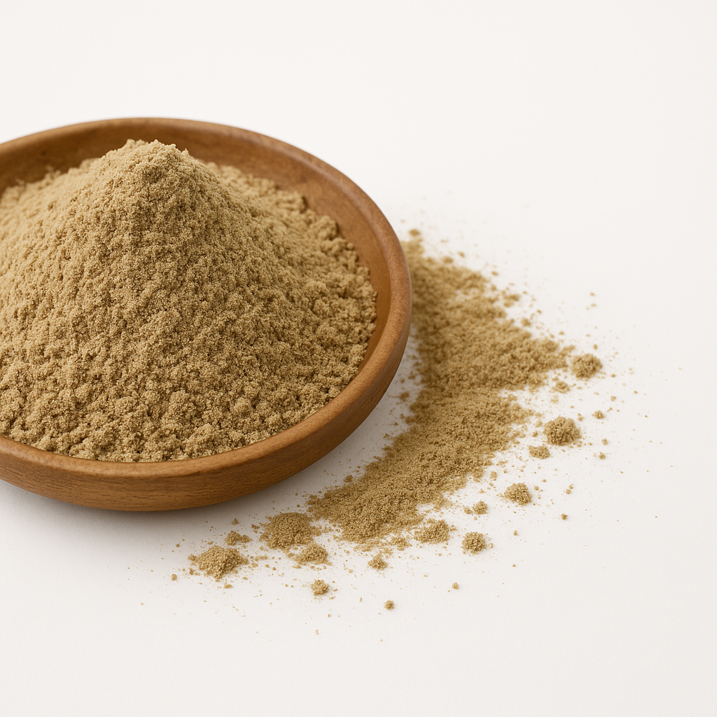 Nærbillede af finmalet beige krydderipulver i en rund træskål med noget pulver spredt ved siden af på hvid baggrund