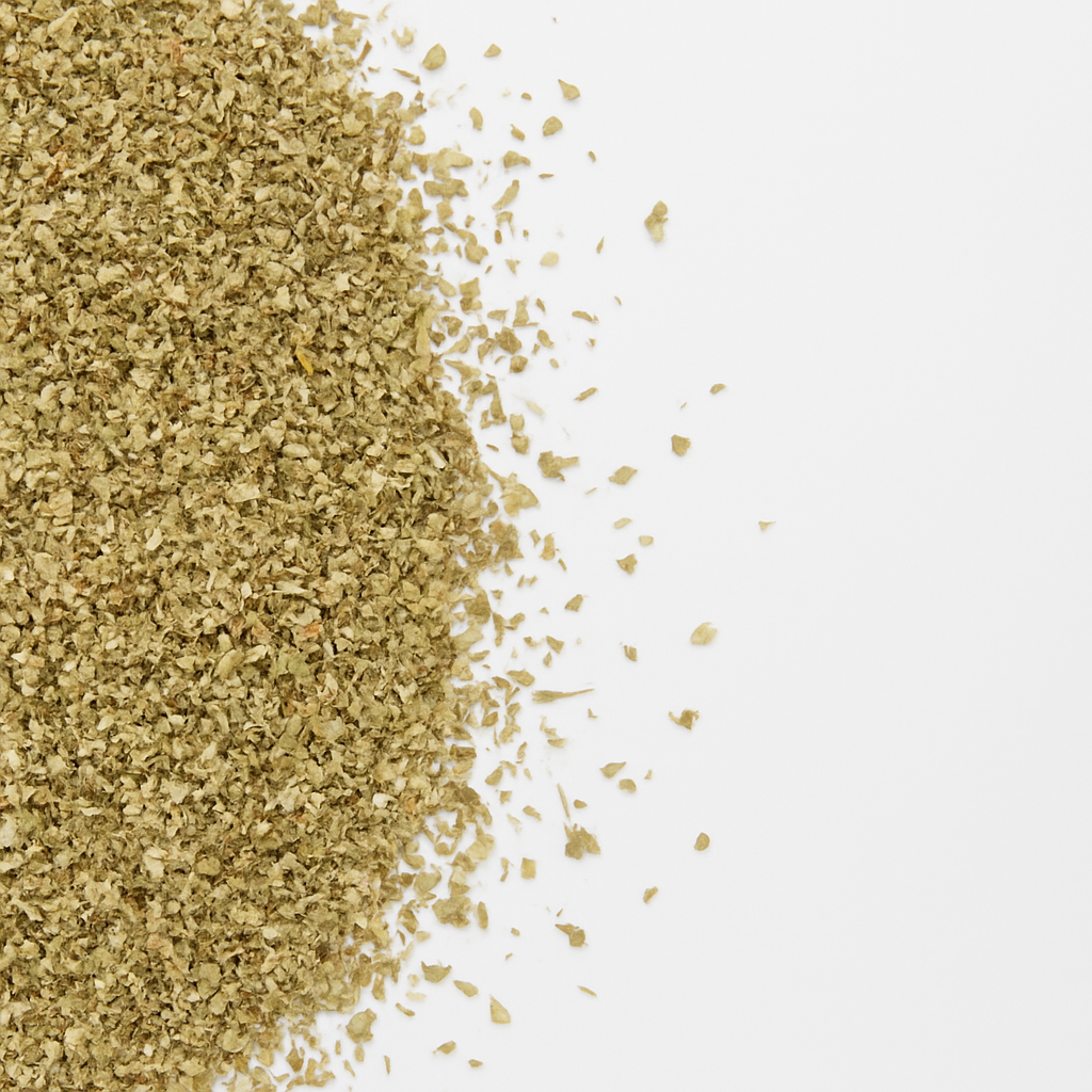 Nærbillede af lysegrønne tørre krydderurteflager spredt på hvid baggrund