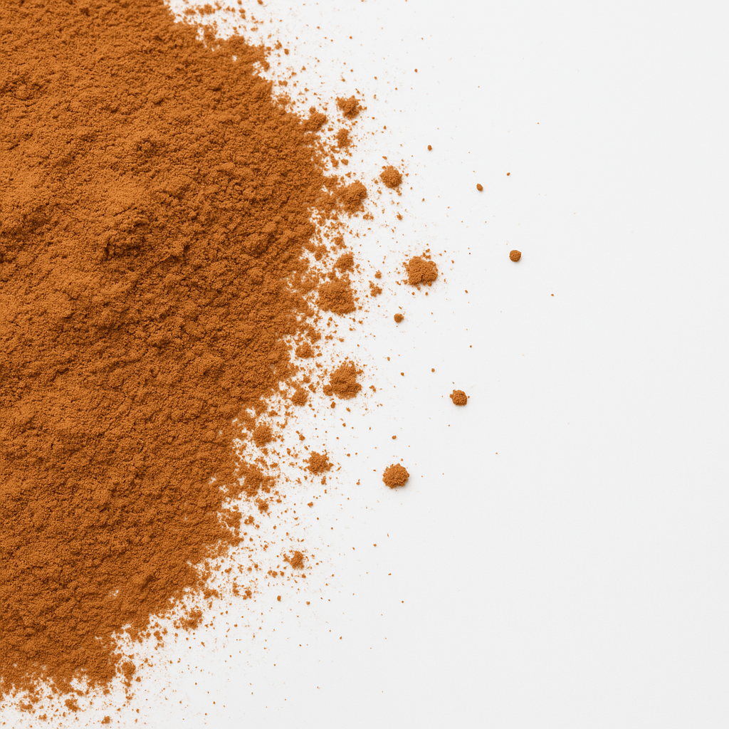 Nærbillede af fint malet kanelpulver spredt på hvid baggrund