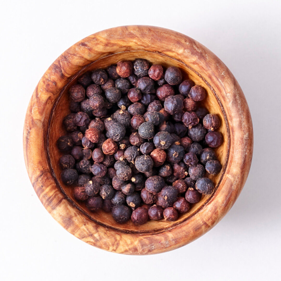 Top view of juniper berries in a rustic wooden bowl