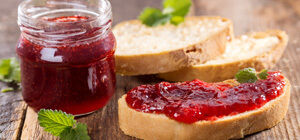 Jar of strawberry jam with fresh bread slices