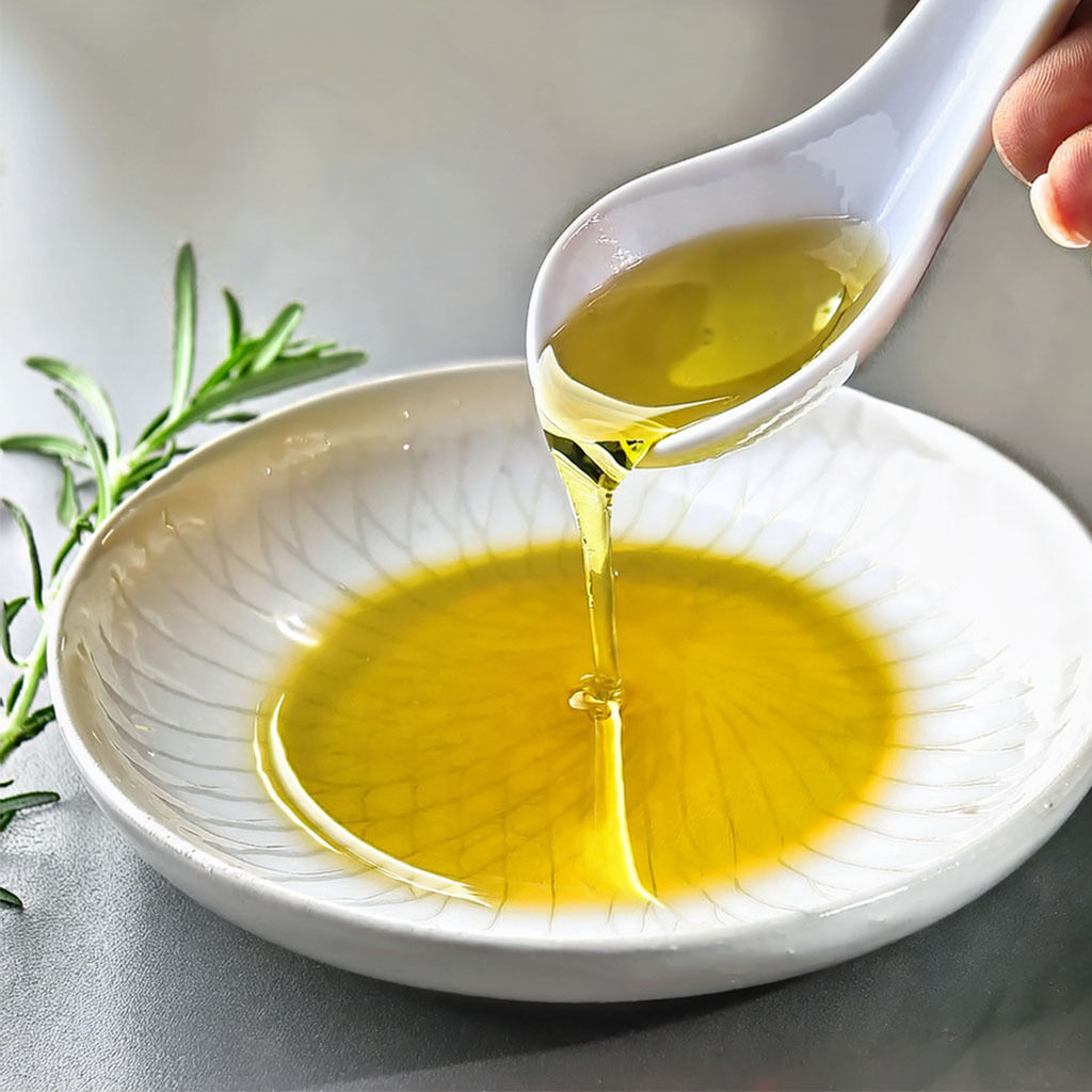 Spoon pouring olive oil into a bowl with rosemary