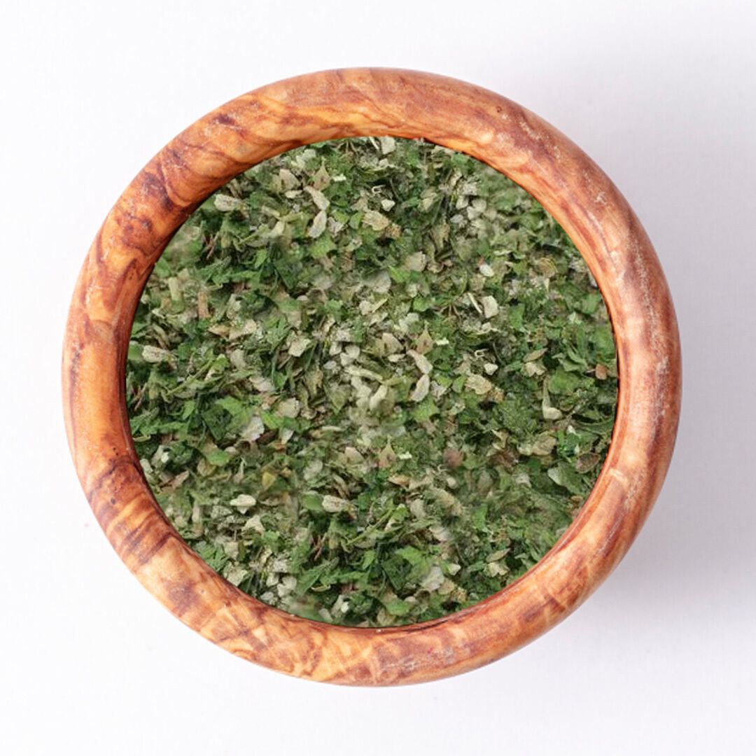 Aerial view of a wooden bowl filled with finely chopped dried herbs