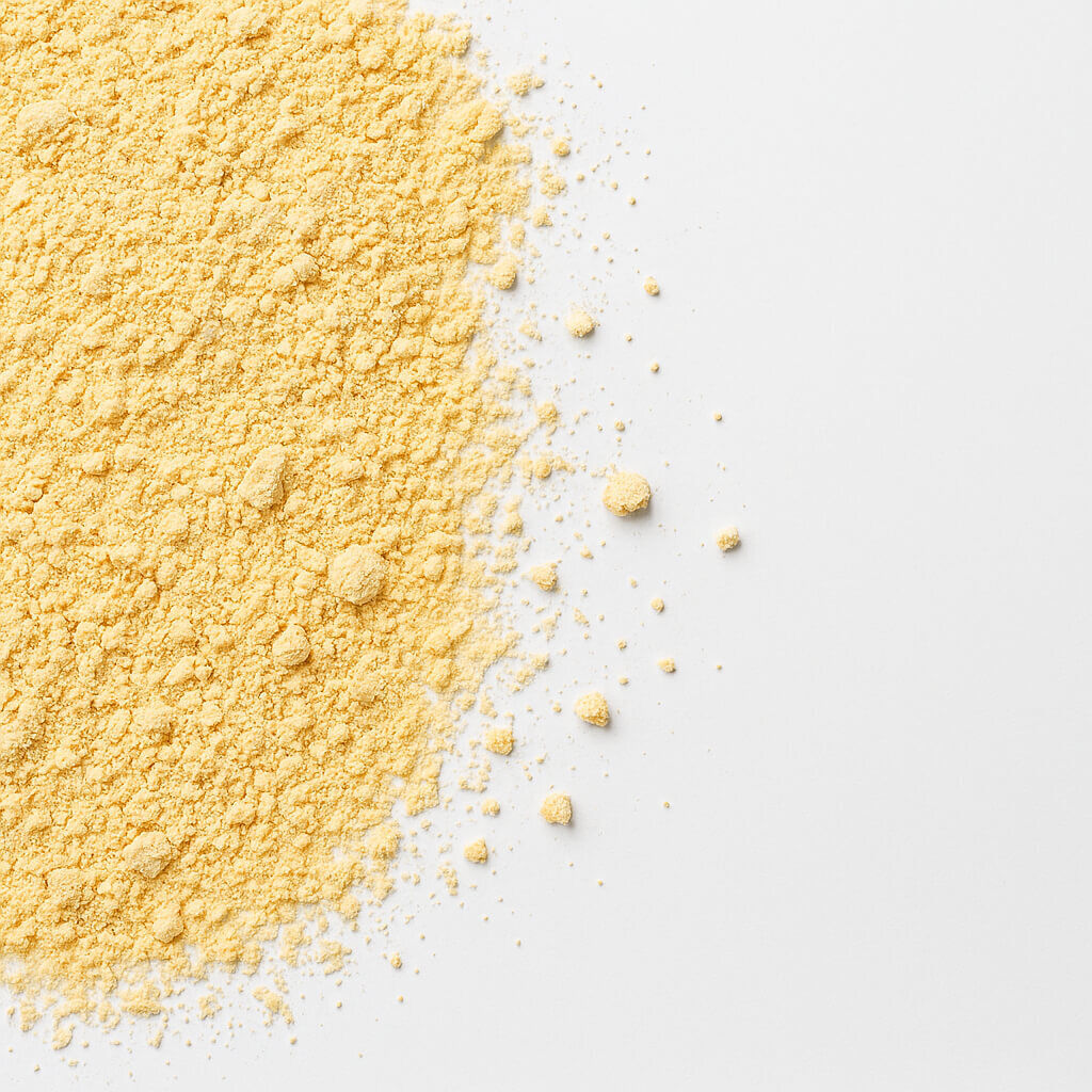 Pile of yellow maize flour with scattered crumbs