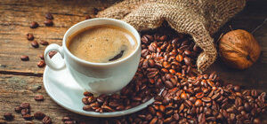 Cup of coffee with roasted beans on wooden table