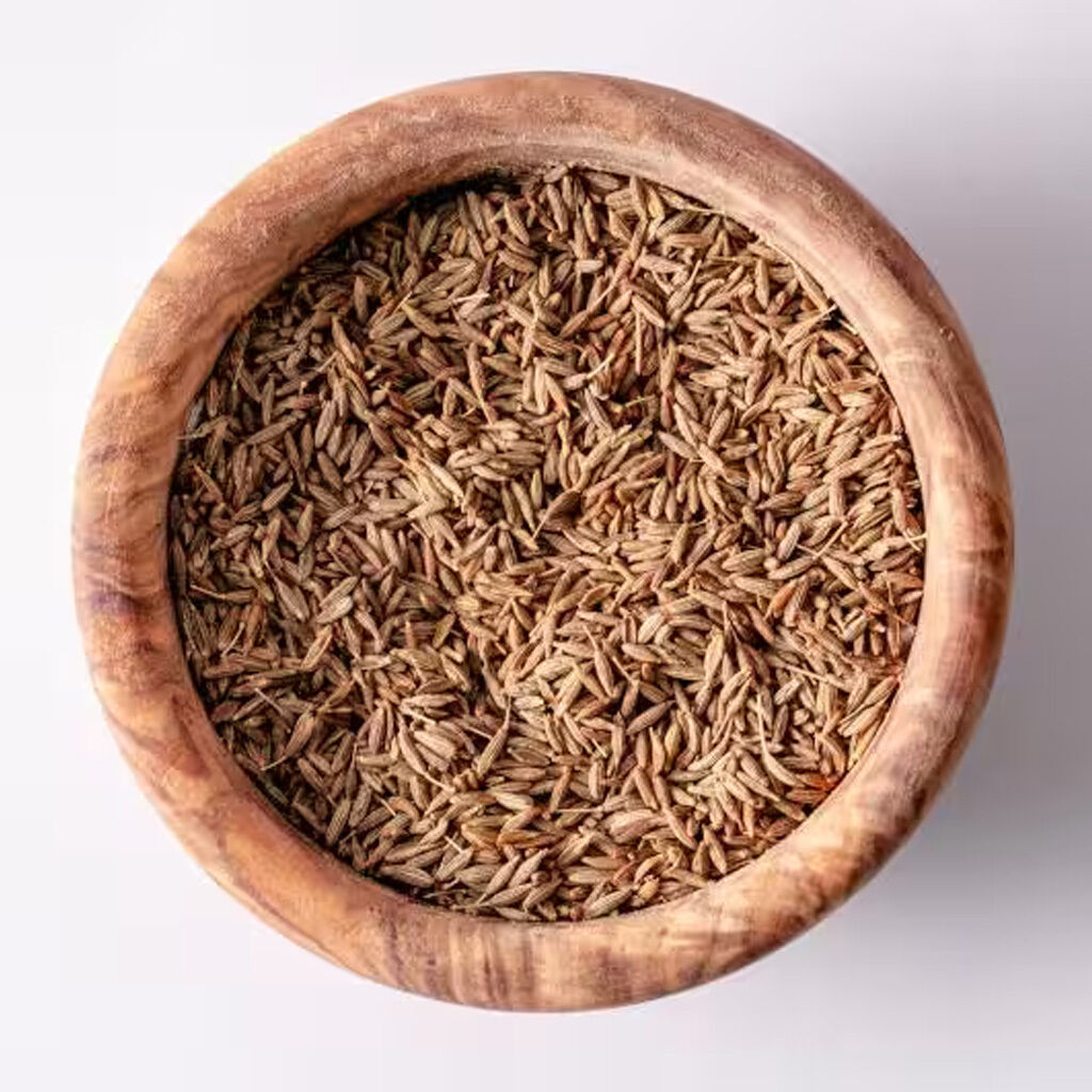 Topbillede af en træskål fyldt med hele spidskommenfrø til madlavning og krydderi