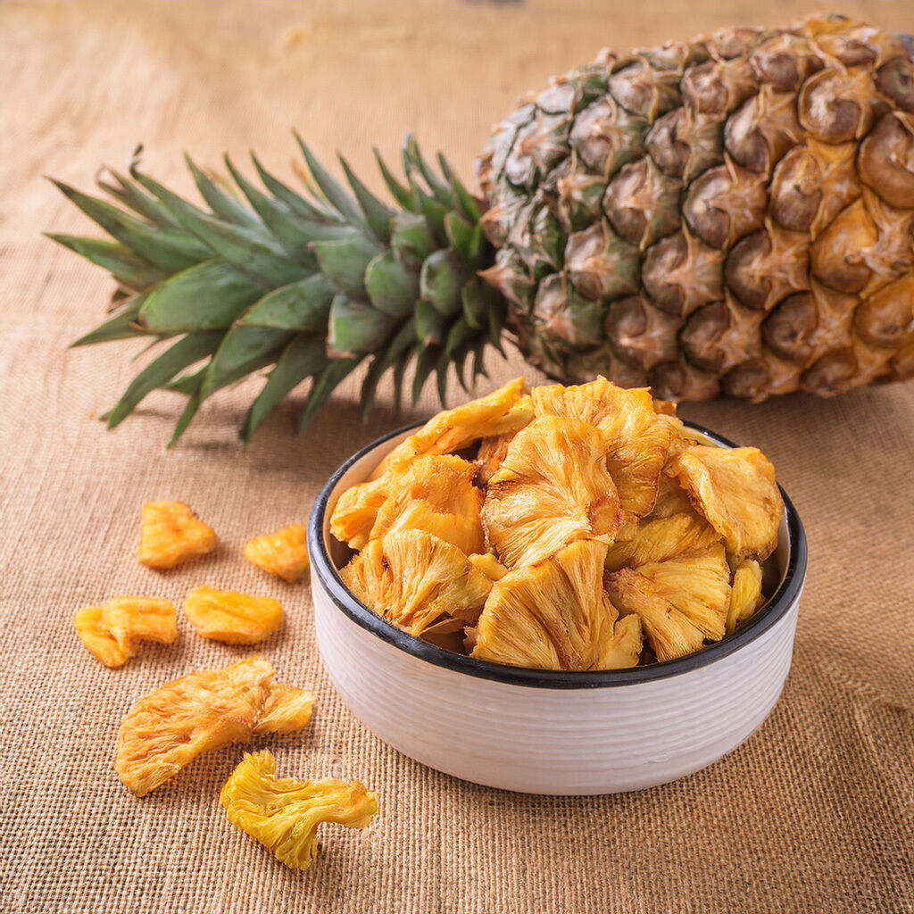 Bowl of dried pineapple slices with whole fruit