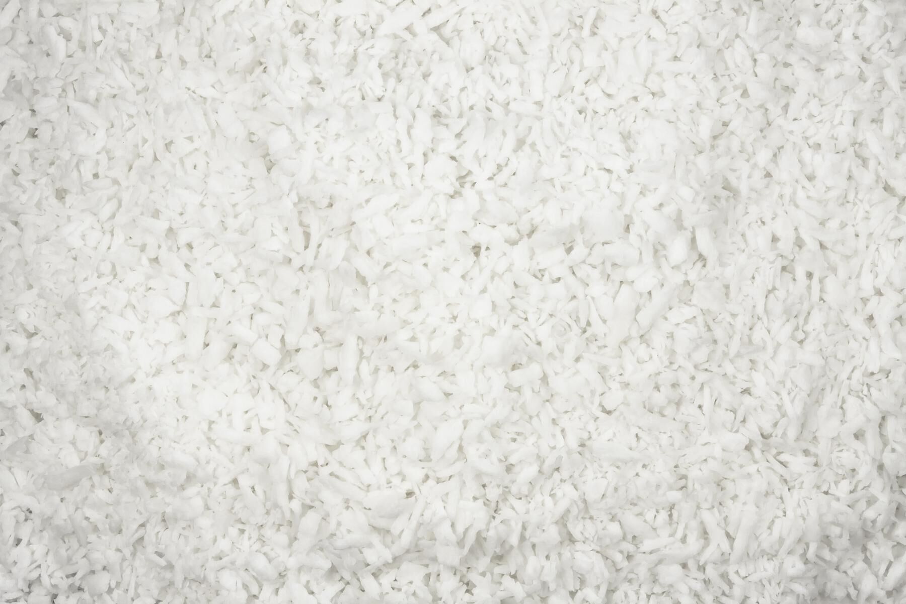 Nærbillede af fintrevne, hvide kokosflager på hvid baggrund