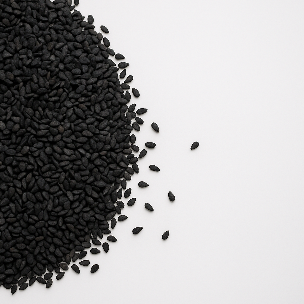 Nærbillede af sorte sesamfrø spredt i en bunke på en hvid overflade