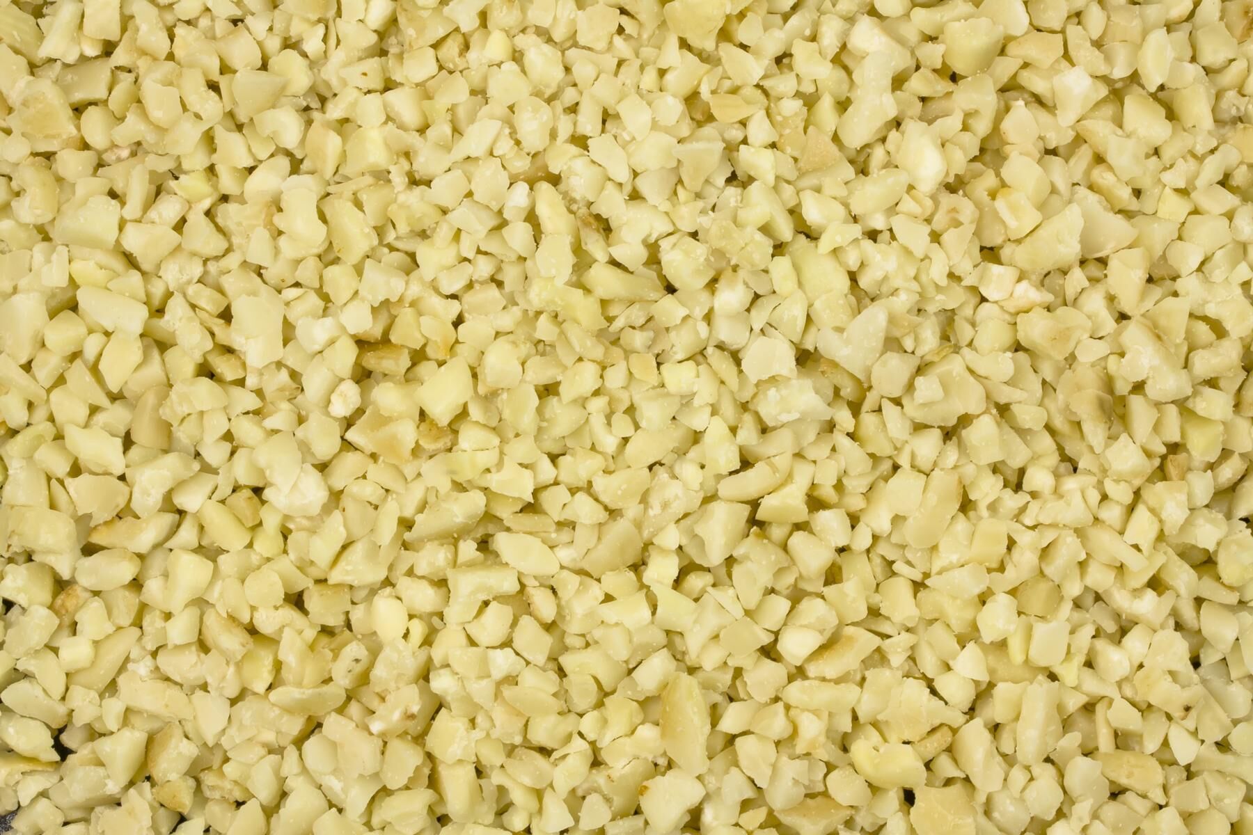 Tæt foto af groft hakkede macadamianødder i lyse, cremede stykker