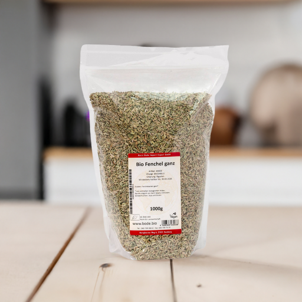 Gennemsigtig genlukkelig pose med økologiske hele fennikelfrø (1 kg) og hvid-rød etiket, stående på køkkenbord