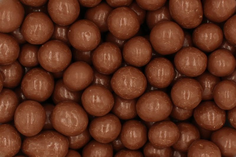 Nahaufnahme zahlreicher glänzender, runder Milchschokoladen-Dragees