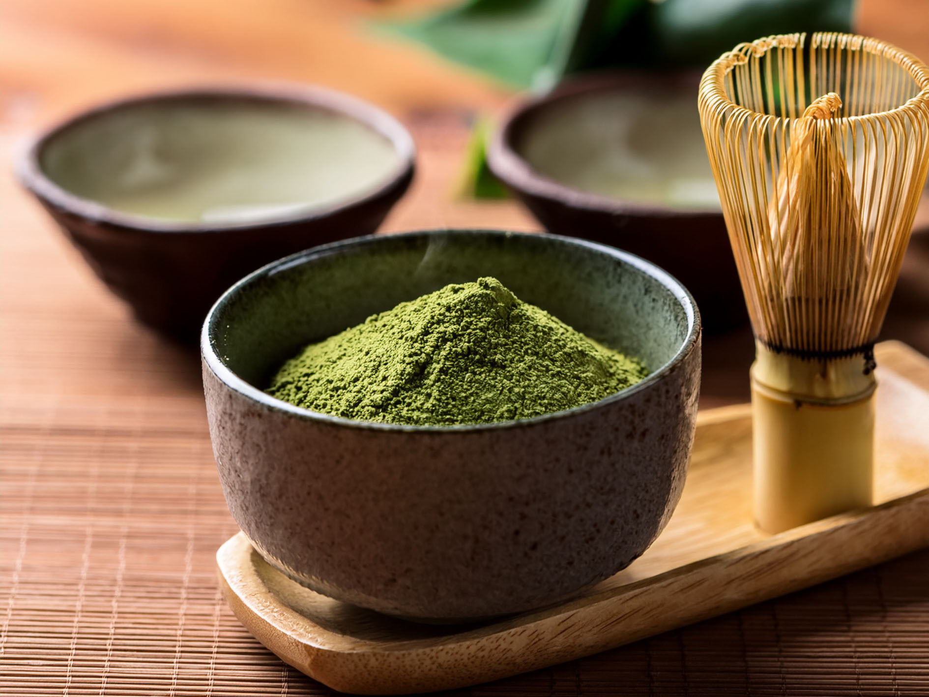 Close-up of matcha powder in ceramic bowl with bamboo whisk