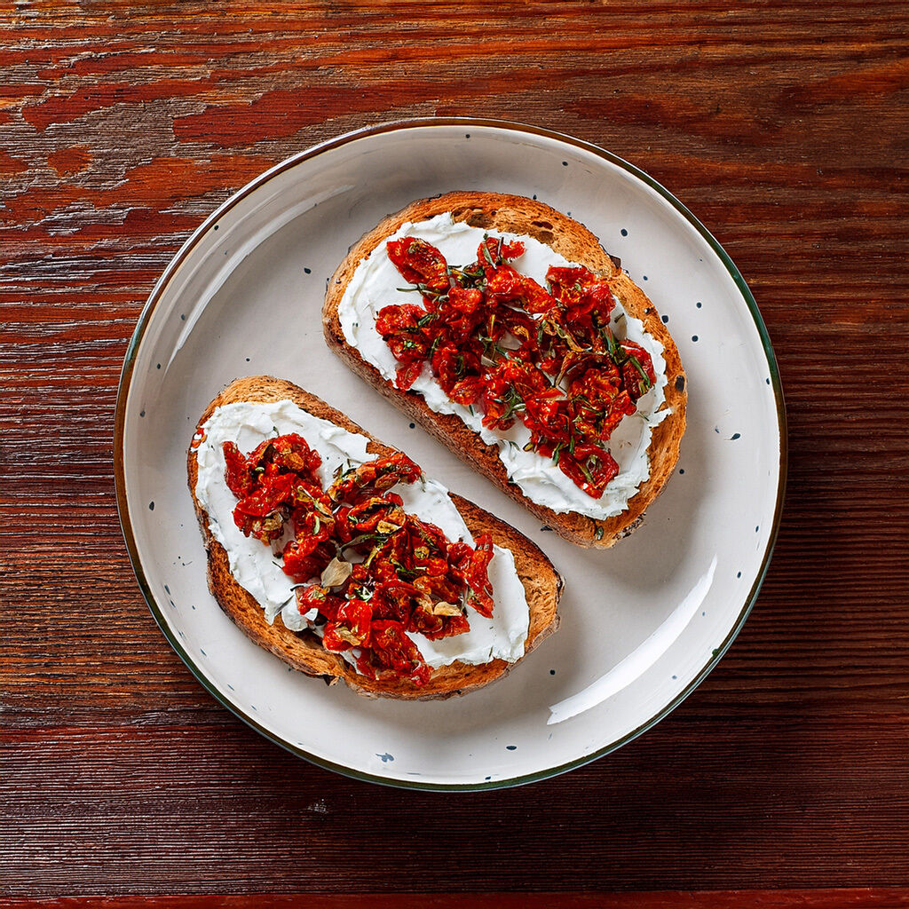 Two slices of toast with cream cheese and sun-dried tomatoes
