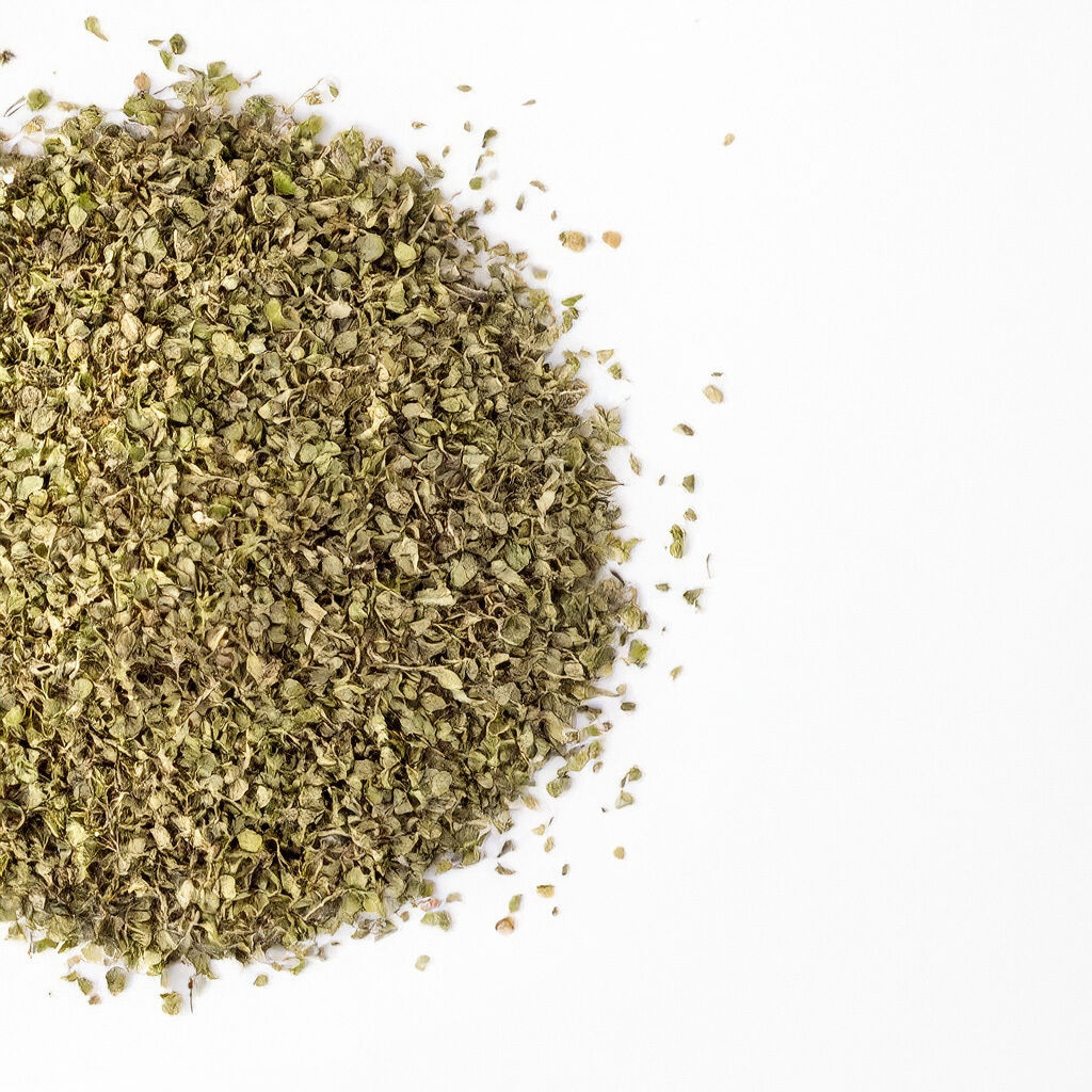 A pile of dried oregano leaves spread across a white background, showing texture and color.